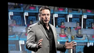 Elon musk giving a speech in front of batteries