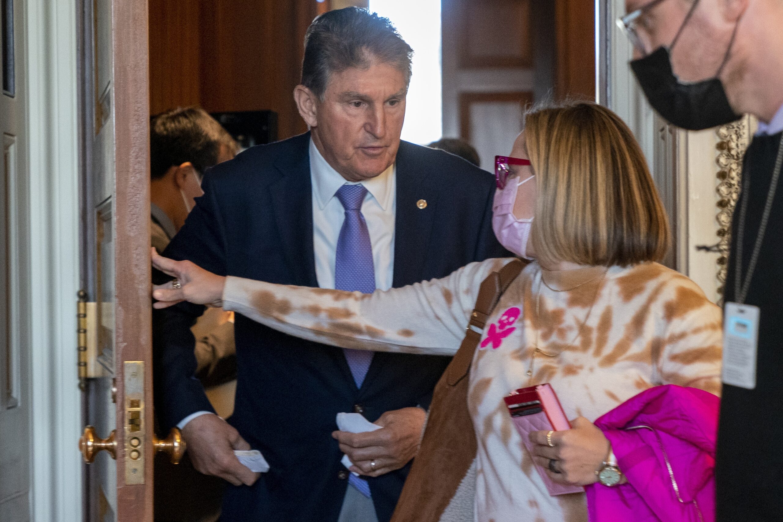 Sen. Kyrsten Sinema, D-Ariz., right, holds the door open for Sen. Joe Manchin, D-W.Va., left, after they attended a Democratic policy luncheon, Tuesday, Nov. 16, 2021, on Capitol Hill in Washington. (AP Photo/Jacquelyn Martin)