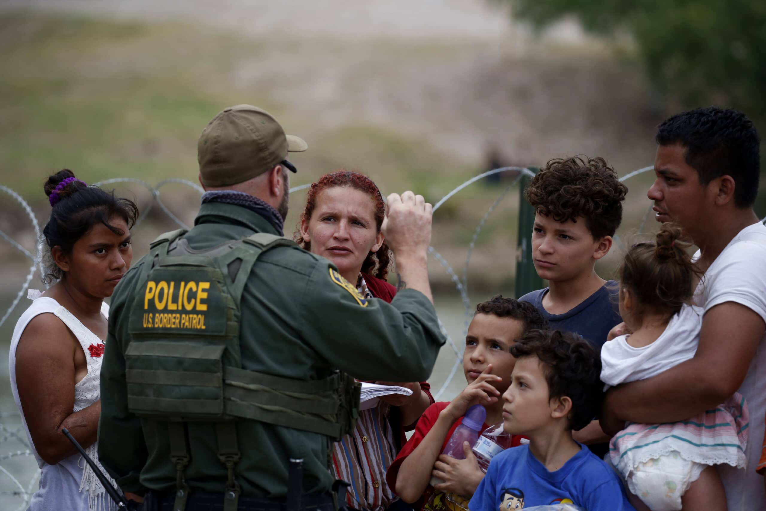 A Border Patrol officer talks to migrants after they crossed the Rio Grande river in Eagle Pass, Texas, Sunday May 22, 2022. The U.S. government has expelled migrants more than 1.9 million times under Title 42, named for a 1944 public health law, denying them a chance to seek asylum as permitted under U.S. law and international treaty for purposes of preventing the spread of COVID-19. President Joe Biden wanted to end Title 42, but a federal judge in Louisiana issued a nationwide injunction that keeps it intact.  (AP Photo/Dario Lopez-Mills)