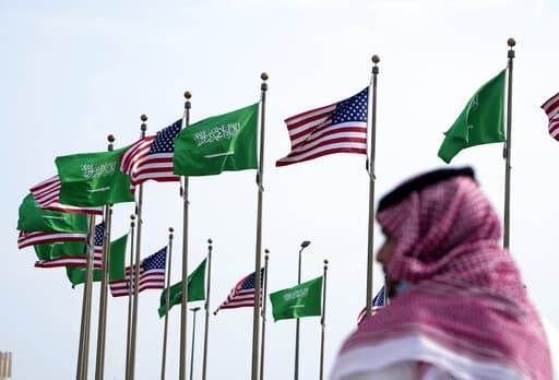FILE - A man stands under American and Saudi Arabian flags prior to a visit by U. S. President Joe Biden, at a square in Jeddah, Saudi Arabia, Thursday, July 14, 2022. As President Joe Biden prepares to meet Saudi Crown Prince Mohammed bin Salman on Friday, the prince's reputation as a brazen leader whose rise to power coincided with a sweeping crackdown on critics will likely cast a shadow on the meeting. (AP Photo/Amr Nabil, File)