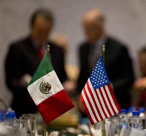 Miniature national flags representing Mexico and the United States stand side by side as California Gov. Jerry Brown, right background, and Mexico's Energy Secretary Pedro Joaquin Coldwell, left background, talk after signing a memorandum of understanding, in Mexico City, Tuesday, July 29, 2014. Brown will take another break in his trade visit to Mexico to talk about immigration reform with religious leaders from Latin America on Tuesday. (AP Photo/Rebecca Blackwell)