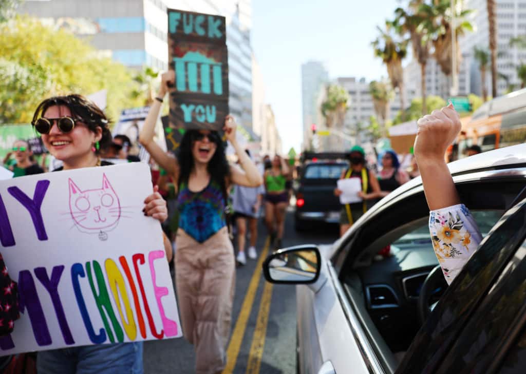 Abortion rights supporters march past a driver raising a fist in support while protesting against the recent U.S. Supreme Court decision to end federal abortion rights protections on June 27, 2022 in Los Angeles, California.