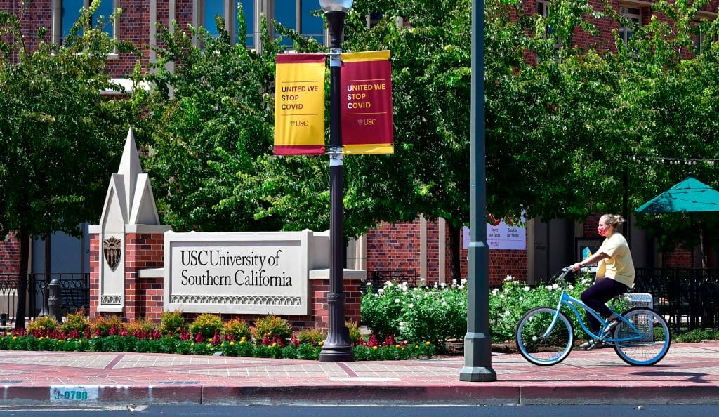 A cyclist wearing a facemask rides her bike at the University of Southern California (USC) in Los Angeles, California on August 25, 2020 where coronavirus cases have seen an alarming increase with more than 100 students in quarantine from cases originating in off-campus housing. (Photo by Frederic J. BROWN / AFP) (Photo by FREDERIC J. BROWN/AFP via Getty Images)