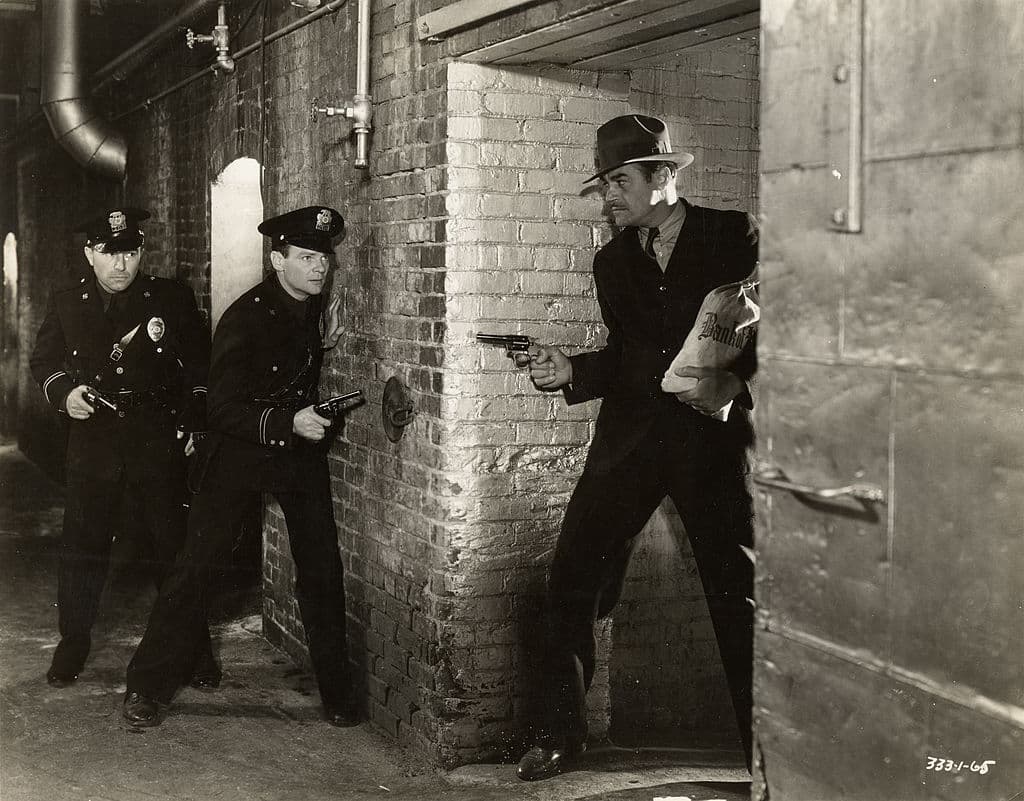 Two police officers lie in wait for a bank robber in a scene from a movie, circa 1940. (Photo by Vintage Images/Getty Images)