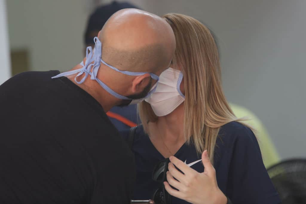 BRASILIA, BRAZIL - MARCH 13:   A couple wearing protective masks kisses at the Asa Norte Regional Hospital (HRAN) on March 13, 2020 in Brasilia, Brazil. According to Health Ministry Brazil has confirmed 77 cases of coronavirus. (Photo by Andre Coelho/Getty Images)