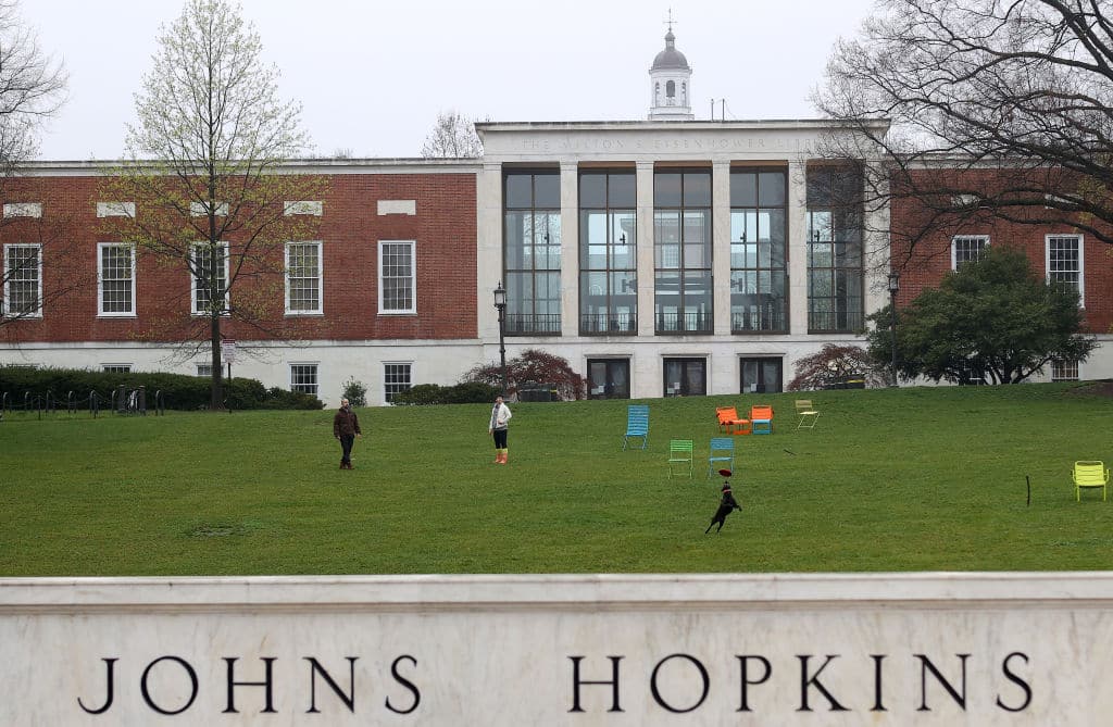 BALTIMORE, MARYLAND - MARCH 28: A couple throw a frisbee for a dog on the campus of The Johns Hopkins University on March 28, 2020 in Baltimore, Maryland. The school is shut down due to the coronavirus (COVID-19) outbreak. (Photo by Rob Carr/Getty Images)