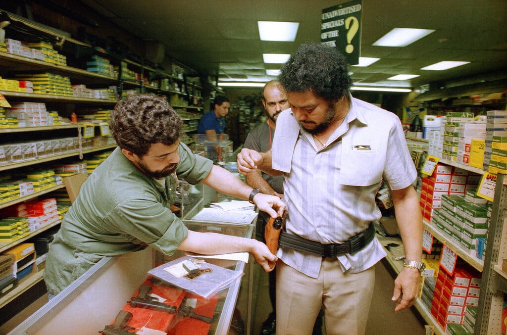 Pedro Bueno, owner of a supermarket in Miami, Fla., stops in the Tamiami Gun Store in Miami, on Oct. 1, 1987, after purchasing a handgun and fitting it to a holster on his side. A new concealed gun law went into effect on Oct. 1, 1987 in Florida, permitting citizens to wear a side-arm as long as they have obtained a state permit. A course in the use and handling of firearms is mandatory in order to obtain the permit. Bueno said someone had stolen another gun he owned and that he was wearing it now because state law permitted it. (AP Photo)