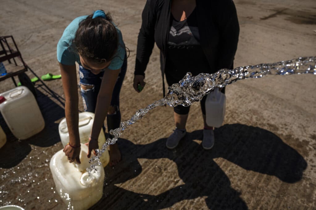 People collect drinking water from a tanker truck one week after Hurricane Ian in La Coloma, in Pinar del Rio province, Cuba, Wednesday, Oct. 5, 2022. (AP Photo/Ramon Espinosa)
