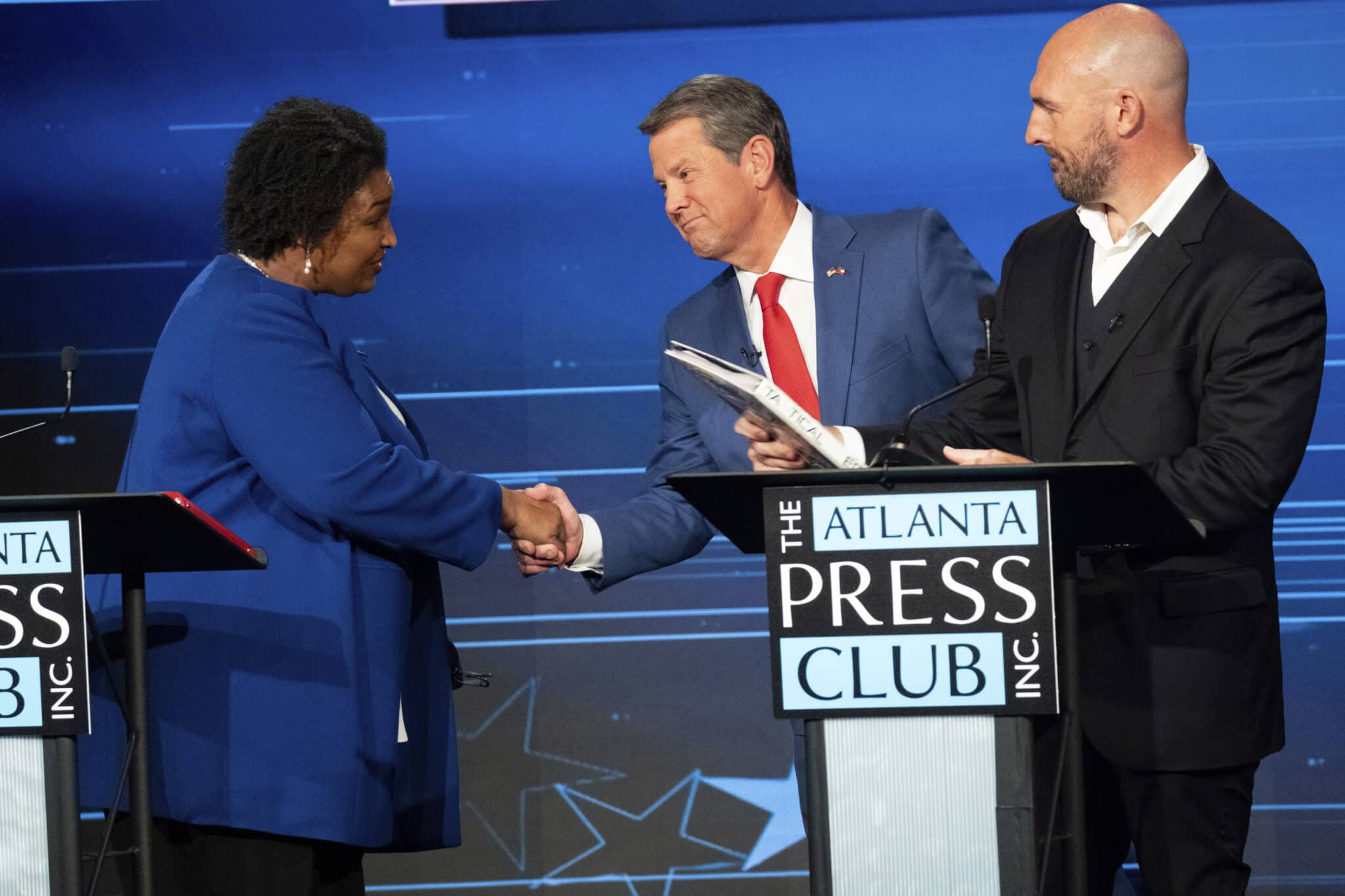 Democratic challenger Stacey Abrams, from left, shakes hands with Georgia Republican Gov. Brian Kemp as Libertarian challenger Shane Hazel stands at right following the Atlanta Press Club Loudermilk-Young Debate Series in Atlanta, Monday, Oct. 17, 2022. (AP Photo/Ben Gray)