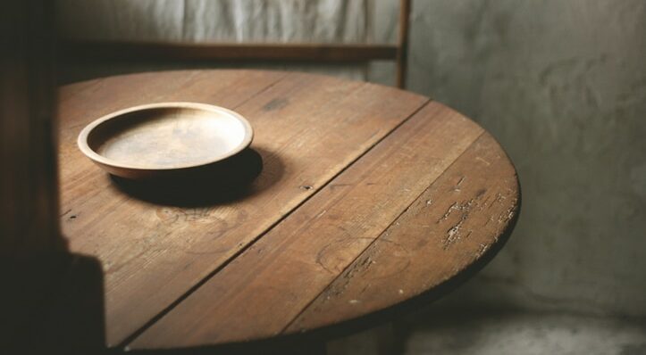 A wooden bowl on an old wooden table,within the kitchen of an old rustic Welsh Cottage.