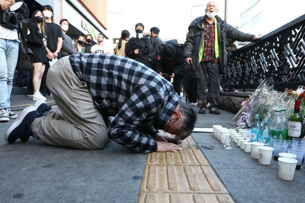 SEOUL, SOUTH KOREA - OCTOBER 30: A man bows as he mourns at the street of a deadly stampede during a Halloween festival on October 30, 2022 in Seoul, South Korea. 151 people have been reported killed and at least 150 others were injured in a deadly stampede in Seoul's Itaewon district, after huge crowds of people gathered for Halloween parties, according to fire authorities. (Photo by Chung Sung-Jun/Getty Images)