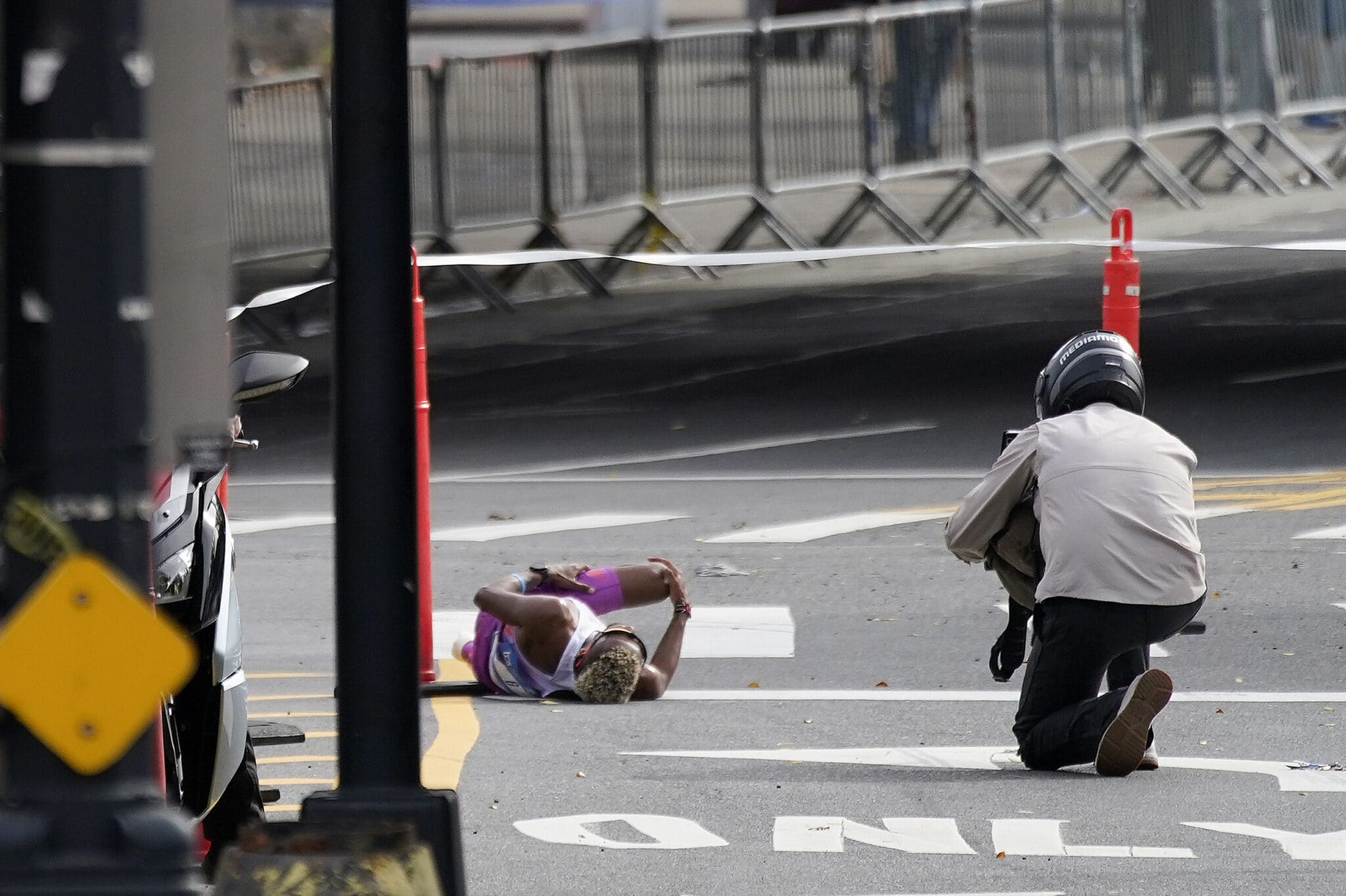 Daniel Do Nascimento, of Brazil, left, lays on the pavement after collapsing in the Bronx borough during the New York City Marathon, Sunday, Nov. 6, 2022, in New York. (AP Photo/Julia Nikhinson)