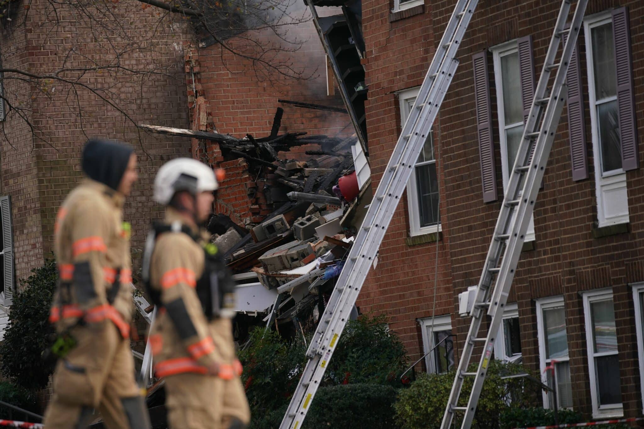Firefighters inspect the site of a fire caused by an explosion at a Gaithersburg, Maryland, apartment building in which 12 people were reported injured on November 16, 2022, according to officials. - A preliminary report by fire department officials indicate the explosion was a gas leak. (Photo by Stefani Reynolds / AFP) (Photo by STEFANI REYNOLDS/AFP via Getty Images)