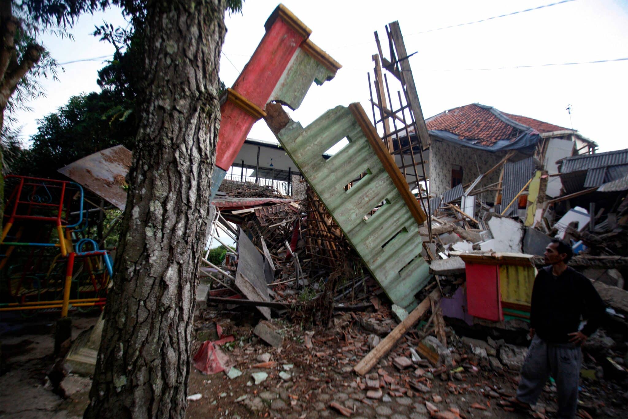 A man stands beside damaged houses following an earthquake in Cianjur on November 21, 2022. - At least 56 people were killed in an earthquake that rattled Indonesia's main island of Java on November 21, 2022, the governor of the worst-hit province said. (Photo by AFP) (Photo by STR/AFP via Getty Images)