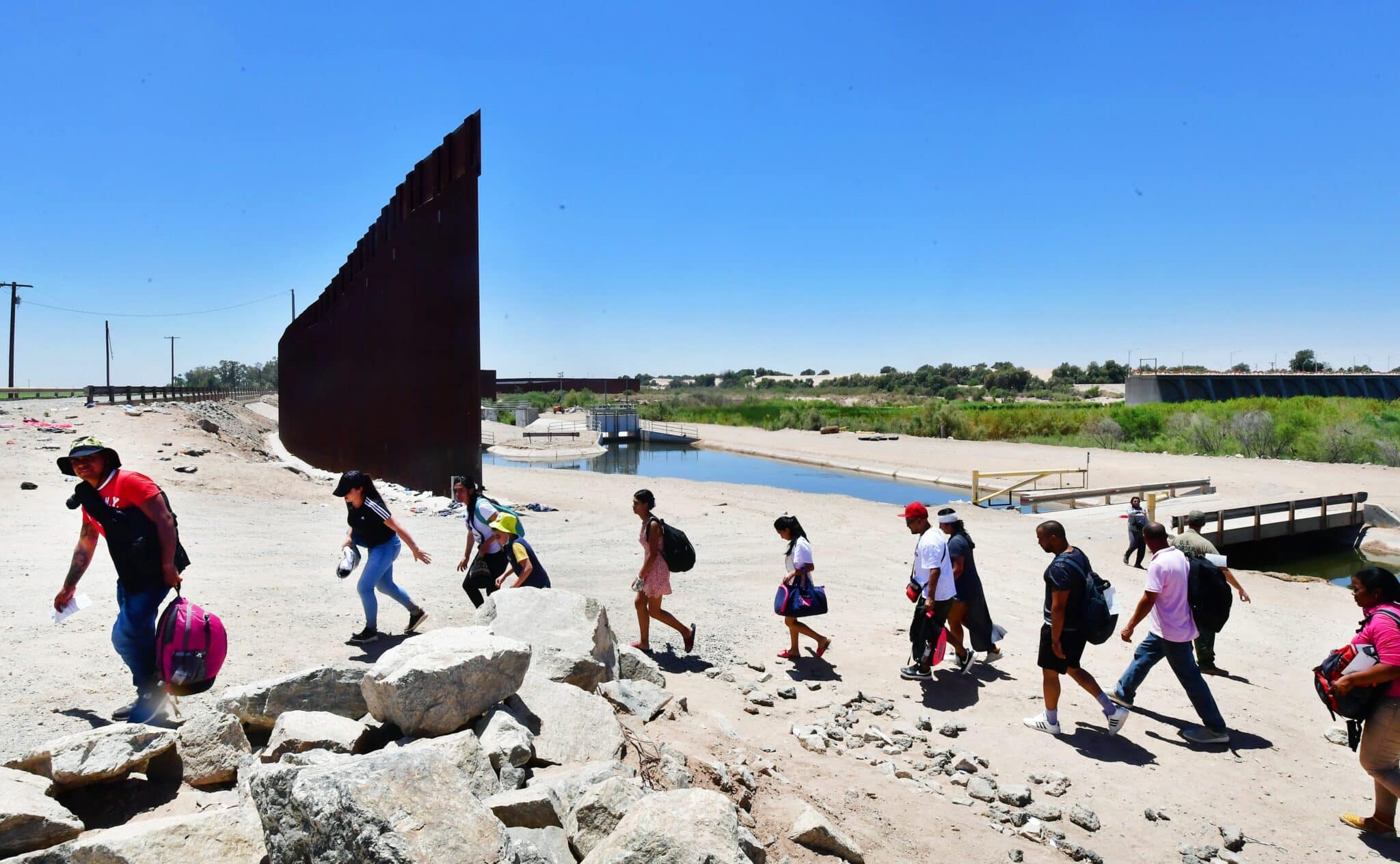 Migrants cross into the US from the Mexico through a gap in the border wall separating the Mexican town of Algodones from Yuma, Arizona, on May 16, 2022. - A US Federal judge is expected to make a ruling on health policy Title 42 which has been used at the border to expel illegal immigrants due to the Covid-19 pandemic. (Photo by Frederic J. BROWN / AFP) (Photo by FREDERIC J. BROWN/AFP via Getty Images)