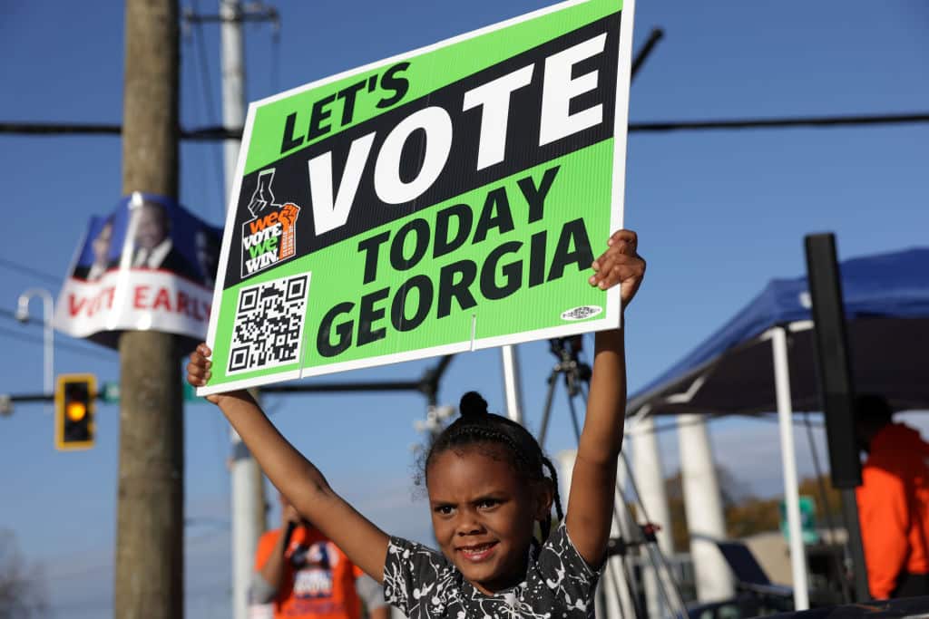 ATLANTA, GEORGIA - NOVEMBER 29: Local resident Reniya Weekes holds a sign to encourage people to vote early outside a polling station on November 29, 2022 in Atlanta, Georgia. Early voting has started in select Georgia counties for a special runoff election days after the Georgia Supreme Court rejected an emergency request from Republicans to block counties from offering early voting.  (Photo by Alex Wong/Getty Images)