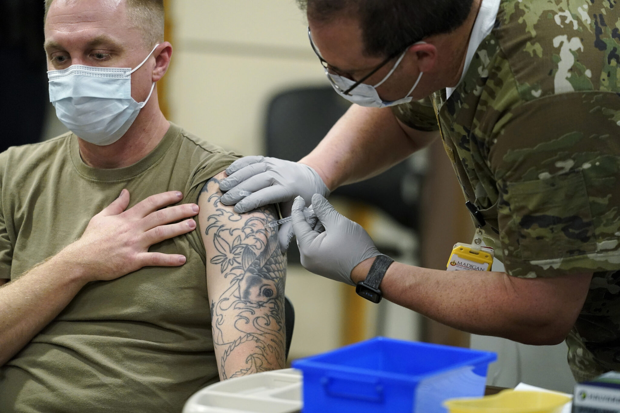 FILE - Staff Sgt. Travis Snyder, left, receives the first dose of the Pfizer COVID-19 vaccine given at Madigan Army Medical Center at Joint Base Lewis-McChord in Washington state, Dec. 16, 2020, south of Seattle. U.S. military forces around the world will no longer be required to get the COVID-19 vaccine. The mandate was lifted under an $858 billion defense spending bill passed by Congress and signed into law Friday by President Joe Biden. (AP Photo/Ted S. Warren, File)