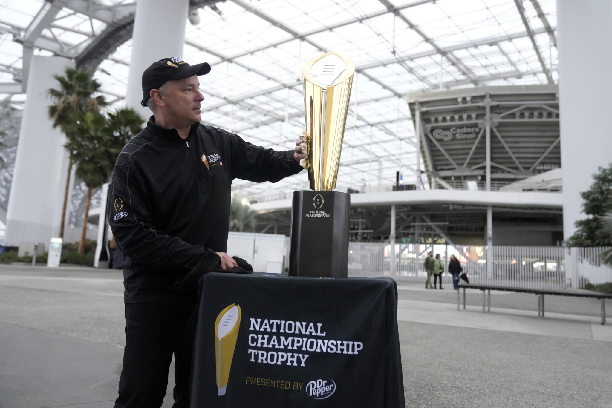 Charley Green cleans the championship trophy Wednesday, Jan. 4, 2023, before a press preview ahead of the CFP NCAA football national championship game at SoFi Stadium in Inglewood, Calif. Georgia faces TCU on Monday for the title. (AP Photo/Marcio Jose Sanchez)