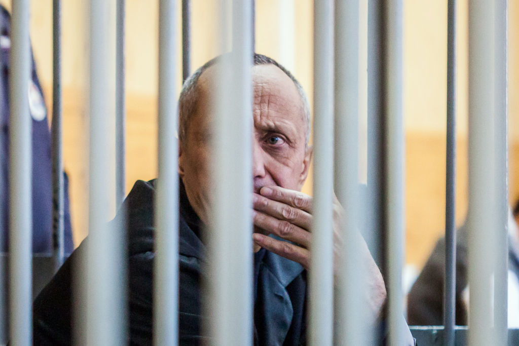 Serial killer Mikhail Popkov sits inside a defendants' cage during a court hearing in Irkutsk on December 10, 2018. - A Siberian policeman who raped and killed women after offering them late-night rides was found guilty of dozens more murders on December 10, 2018, making him Russia's most prolific serial killer of recent times. A court in the city of Irkutsk found Mikhail Popkov guilty of 56 murders between 1992 and 2007, sentencing him to a second life term. He was already in prison after being convicted of killing 22 women in 2015. (Photo by Anton KLIMOV / AFP) (Photo by ANTON KLIMOV/AFP via Getty Images)