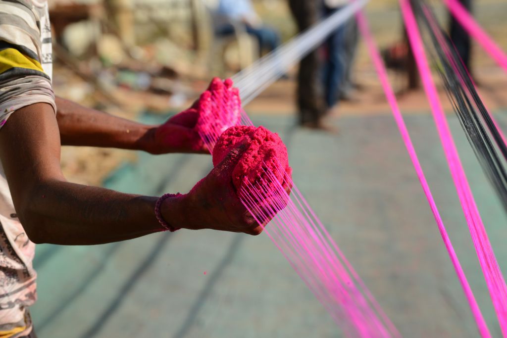Indian workers prepare strings coated with powdered glass used for flying kites ahead of 'Uttarayan' festival, in Ahmedabad on December 30, 2018. - 'Uttarayan' or the Kite Festival is celebrated in Gujarat and elsewhere in India on January 14 every year. (Photo by SAM PANTHAKY / AFP)        (Photo credit should read SAM PANTHAKY/AFP via Getty Images)