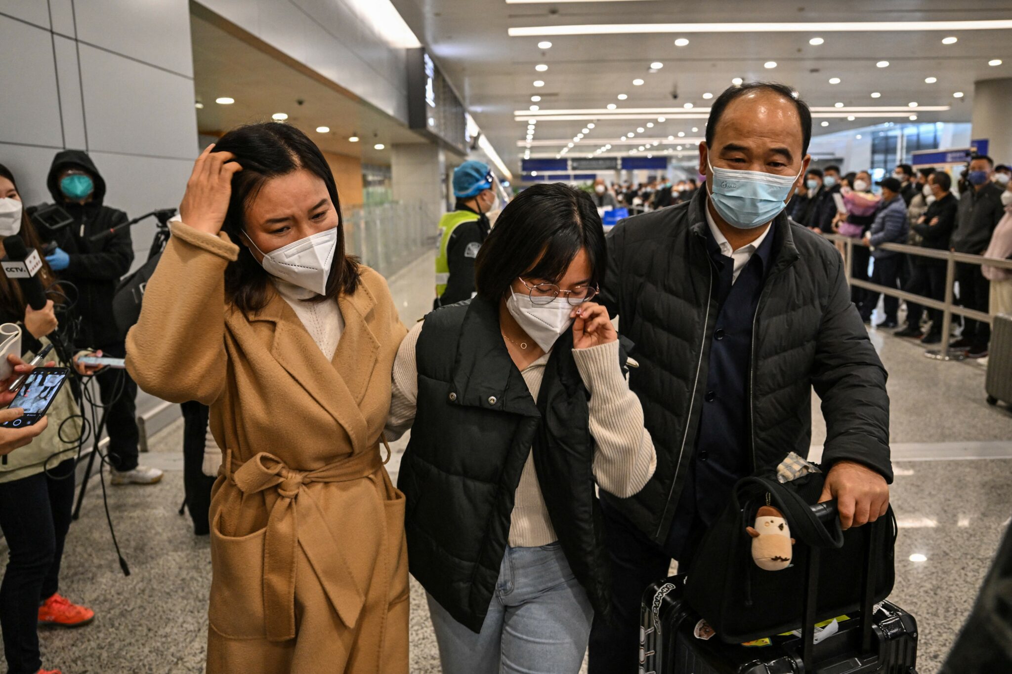 A passenger (C) receives a hug while leaving the arrival area of international flights at the Shanghai Pudong International Airport, in Shanghai on January 8, 2023. - China lifted quarantine requirements for inbound travellers on January 8, ending almost three years of self-imposed isolation even as the country battles a surge in Covid cases. (Photo by Hector RETAMAL / AFP) (Photo by HECTOR RETAMAL/AFP via Getty Images)