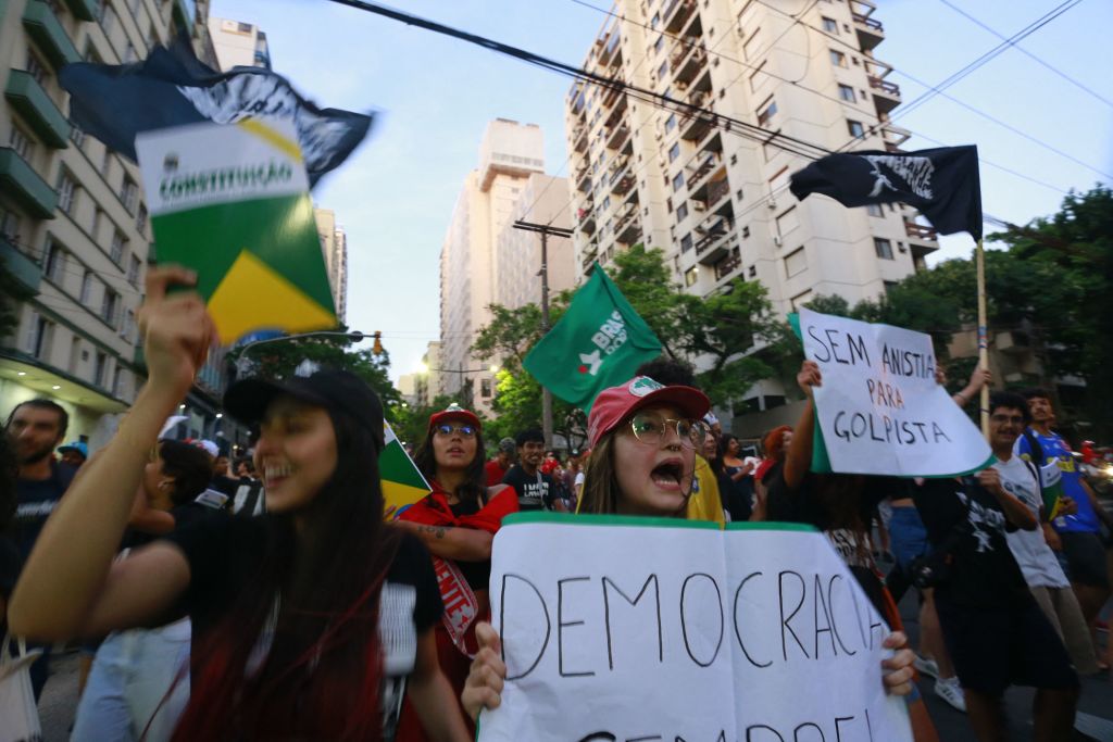 Members of social movements protest in defense of democracy in Porto Alegre, in southern Brazil, on January 9, 2023, a day after supporters of Brazil's far-right ex-president Jair Bolsonaro invaded the Congress, presidential palace, and Supreme Court in Brasilia. - Brazilian security forces locked down the area around Congress, the presidential palace and the Supreme Court Monday, a day after supporters of ex-president Jair Bolsonaro stormed the seat of power in riots that triggered an international outcry. Hardline Bolsonaro supporters have been protesting outside army bases calling for a military intervention to stop Lula from taking power since his election win. (Photo by SILVIO AVILA / AFP) (Photo by SILVIO AVILA/AFP via Getty Images)