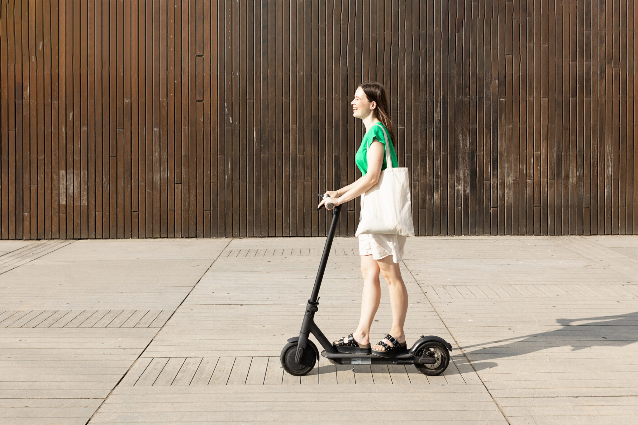 Smiling young woman riding an electric scooter outdoors. Eco-friendly transport and urban lifestyle concept.