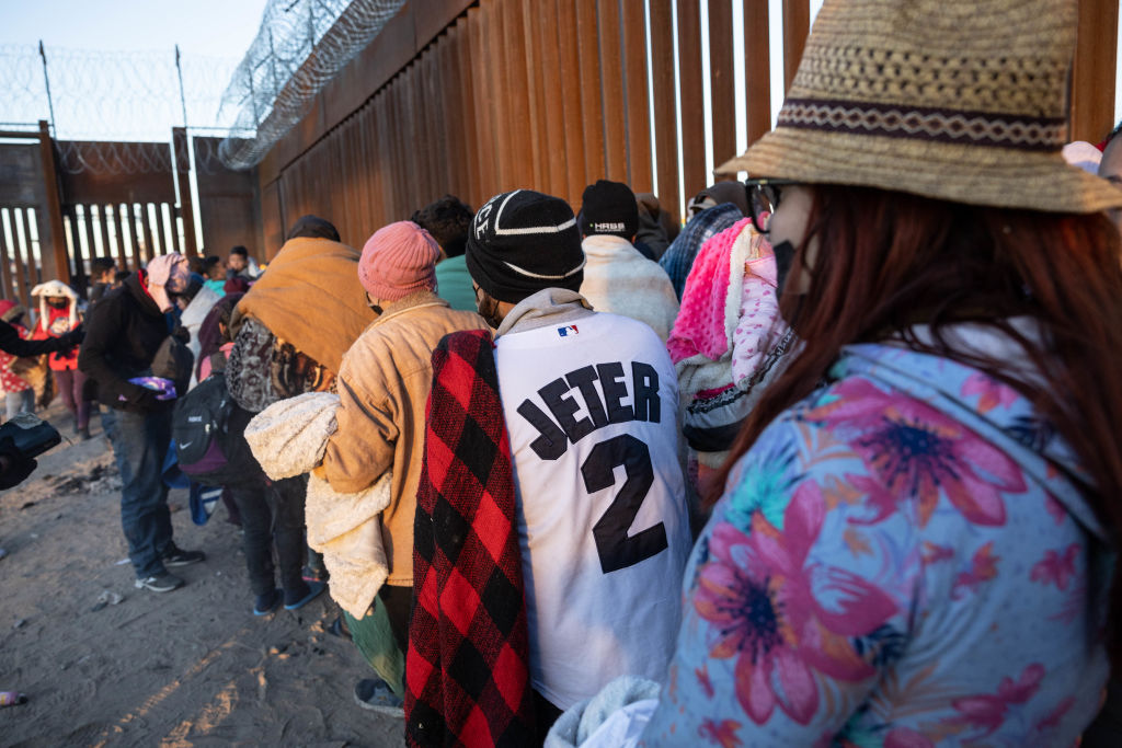 EL PASO, TEXAS - DECEMBER 22: Immigrants line up to present themselves to U.S. Border Patrol agents after spending the night camped alongside the U.S.-Mexico border fence on December 22, 2022 in El Paso, Texas. A spike in the number of migrants seeking asylum in the United States has challenged local, state and federal authorities. The numbers are expected to increase as the fate of the Title 42 authority to expel migrants remains in limbo pending a Supreme Court decision expected after Christmas.  (Photo by John Moore/Getty Images)