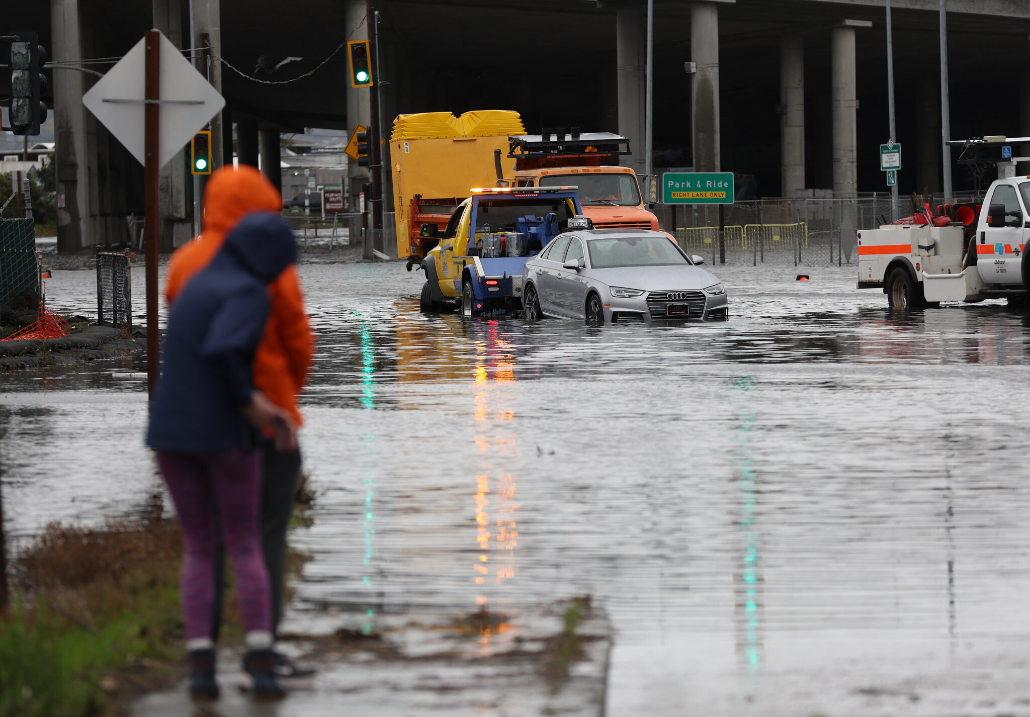 MILL VALLEY, CALIFORNIA - JANUARY 04: People look on as a tow truck pulls a car out of a flooded intersection on January 04, 2023 in Mill Valley, California. A massive storm is hitting Northern California bringing flooding rains and damaging wind (Photo by Justin Sullivan/Getty Images)