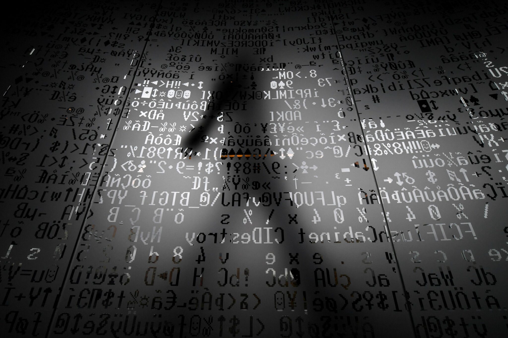 TOPSHOT - A picture taken on October 17, 2016 shows an employee walking behind a glass wall with machine coding symbols at the headquarters of Internet security giant Kaspersky in Moscow. / AFP / Kirill KUDRYAVTSEV / TO GO WITH AFP STORY BY Thibault MARCHAND        (Photo credit should read KIRILL KUDRYAVTSEV/AFP via Getty Images)