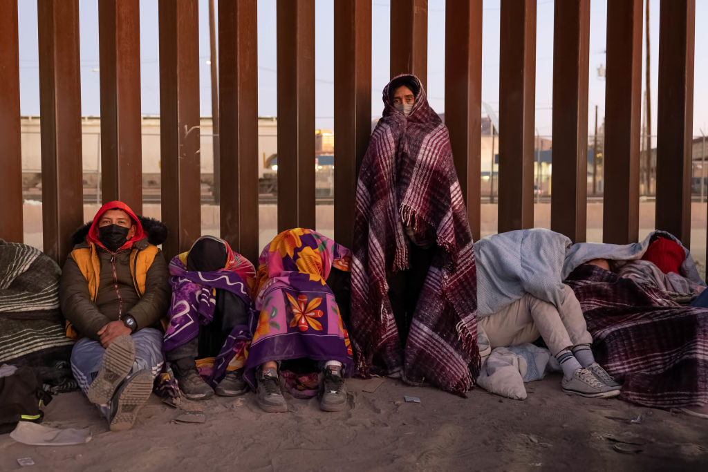 EL PASO, TEXAS - DECEMBER 22: Immigrants bundle up against the cold after spending the night outside along the U.S.-Mexico border fence on December 22, 2022 in El Paso, Texas. A spike in the number of migrants seeking asylum in the United States has challenged local, state and federal authorities. The numbers are expected to increase as the fate of the Title 42 authority to expel migrants remains in limbo pending a Supreme Court decision expected after Christmas.  (Photo by John Moore/Getty Images)
